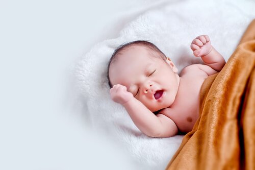 Bébé Couché Sur Une Fourrure Blanche Avec Une Couverture Marron